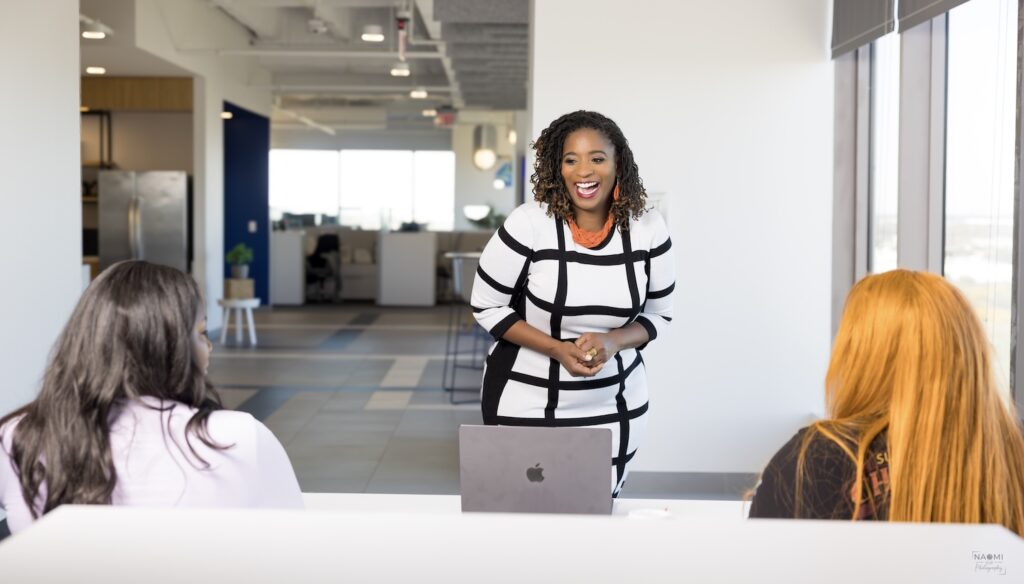 Black woman smiling with a white dress with black stripes smiling and laughing